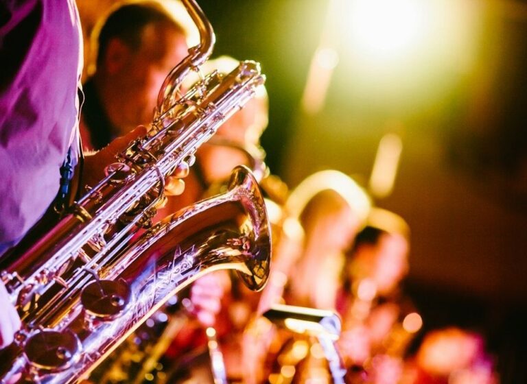 Saxophonist performing with a jazz ensemble under colorful stage lights
