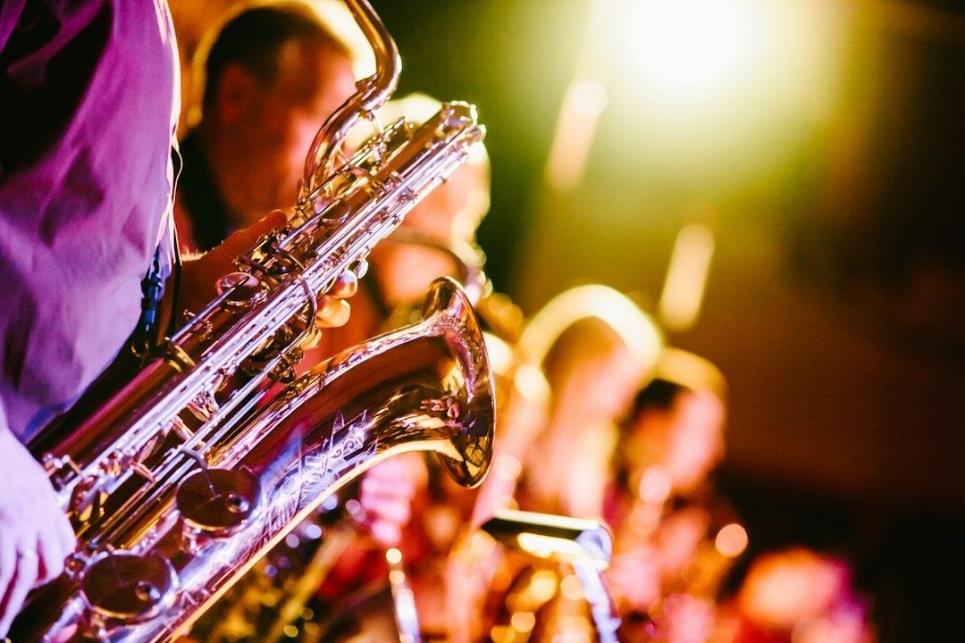 Saxophonist performing with a jazz ensemble under colorful stage lights