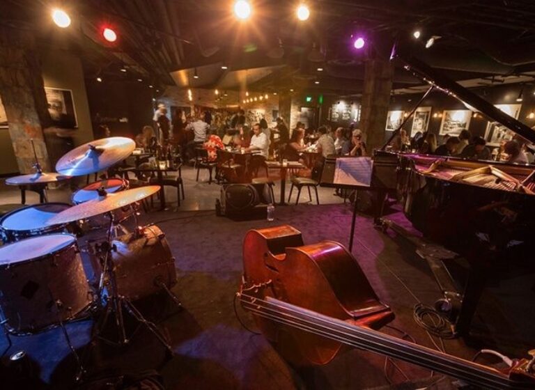 Small jazz club with drums, upright bass, and grand piano