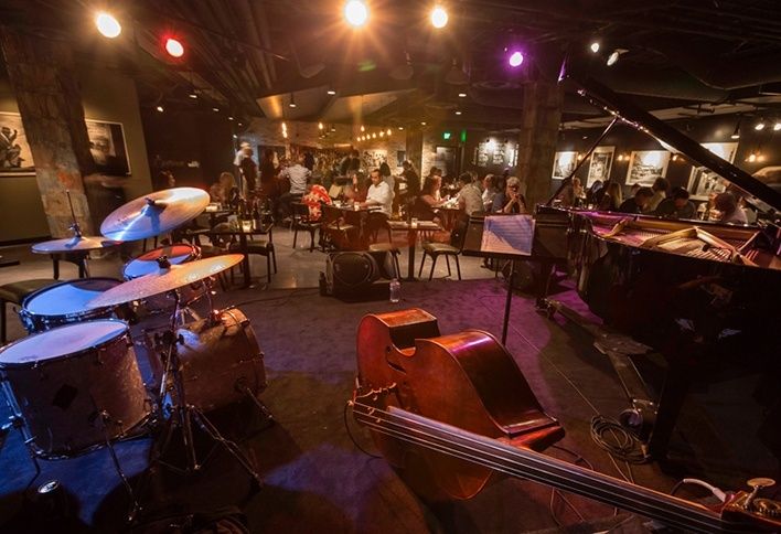 Small jazz club with drums, upright bass, and grand piano